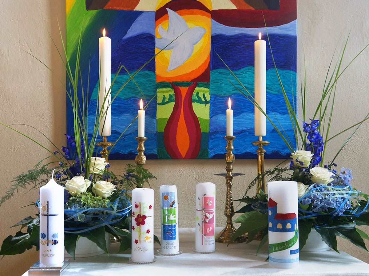 Taufkerzen auf einem Altar mit farbenfrohem Bild