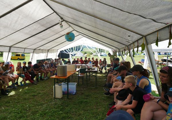 Kinder sitzen im Kreis in einem großen Zelt